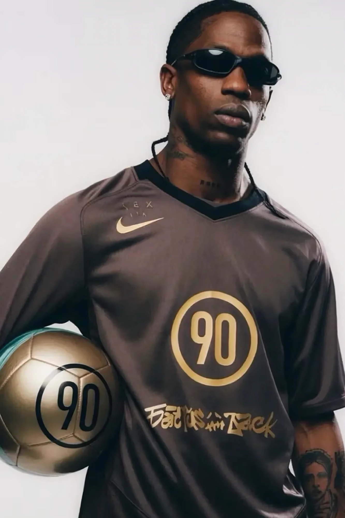 Travis Scott wearing the brown Cactus Jack x Nike Total 90 jersey with a golden ball featuring the 90 logo