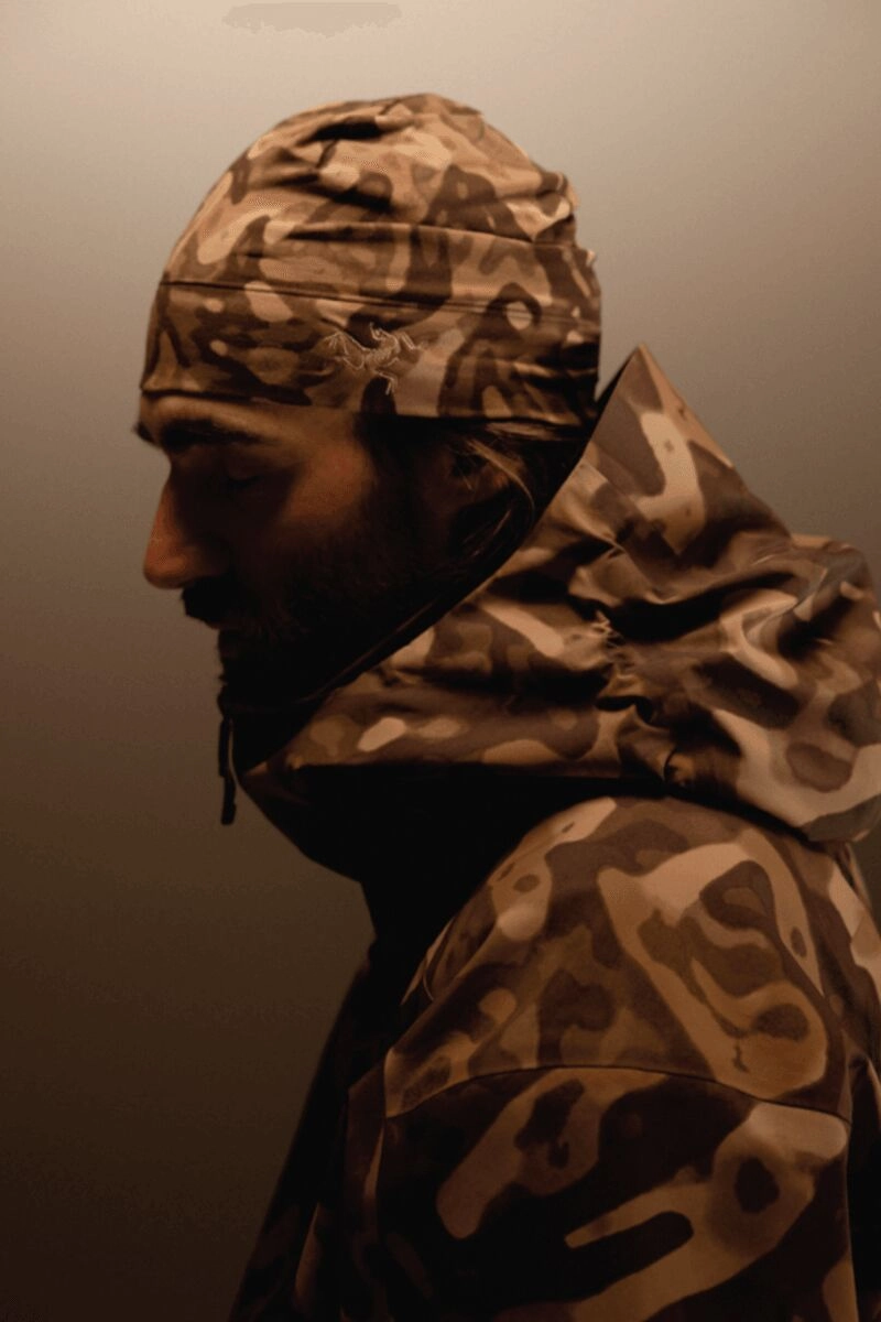 Homme de profil portant une veste Arc'teryx Grottoflage marron