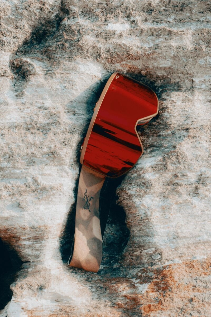 Red Arc'teryx Atomic goggles placed on a rock with mirror reflection