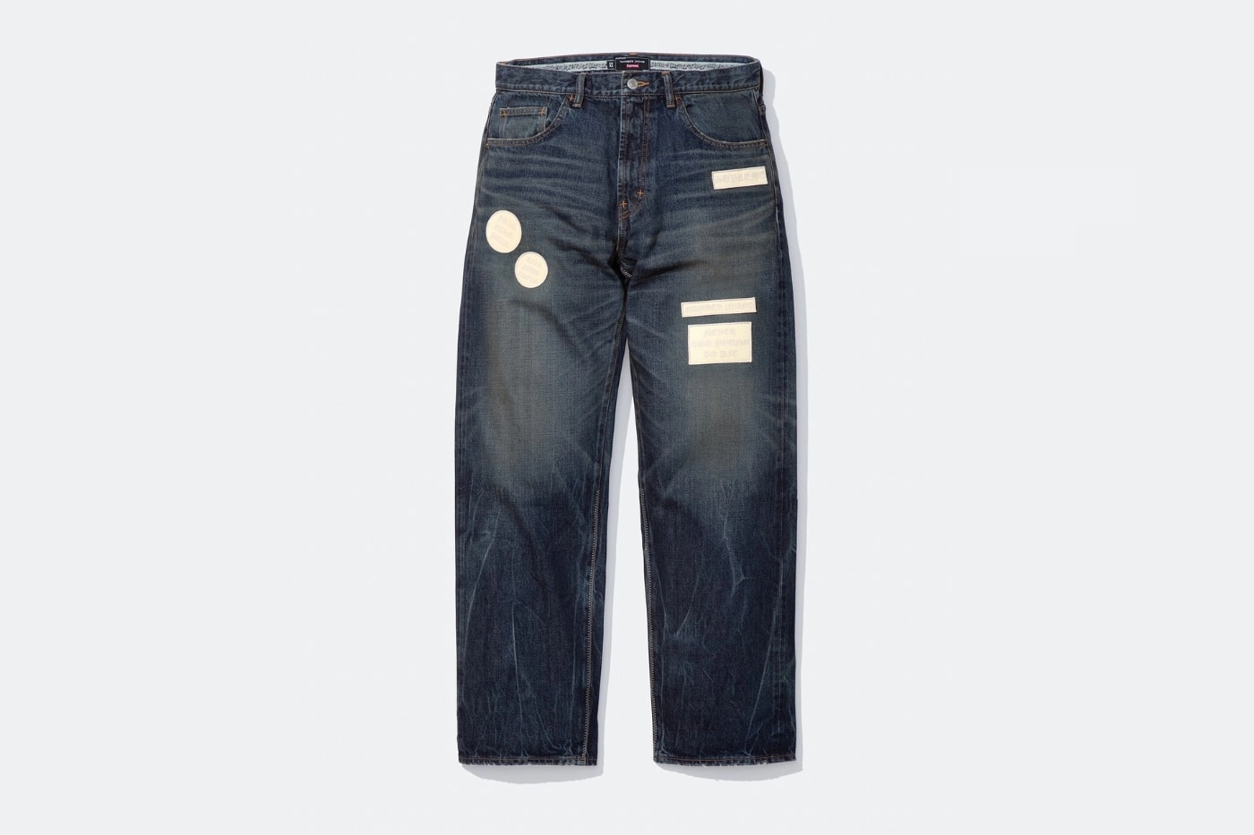jean bleu Supreme x Number Nine avec patchs blancs sur fond blanc