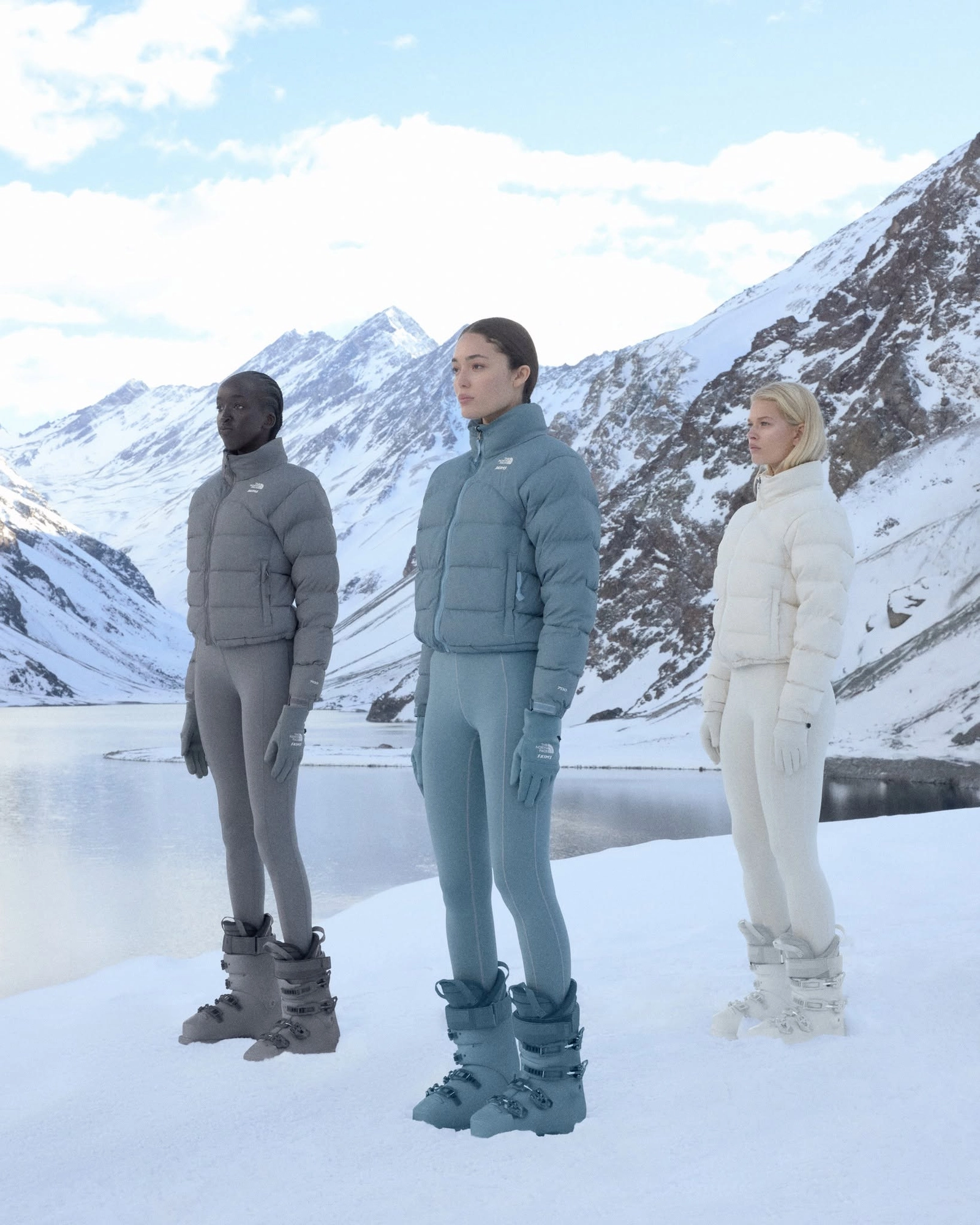 Three models wearing The North Face x Skims outfits in a snowy landscape