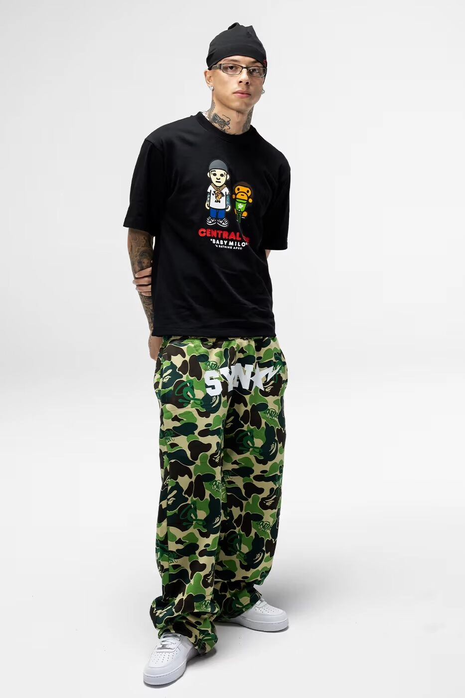 Central Cee wearing black t-shirt Central Cee x BAPE and camouflage pants on white background
