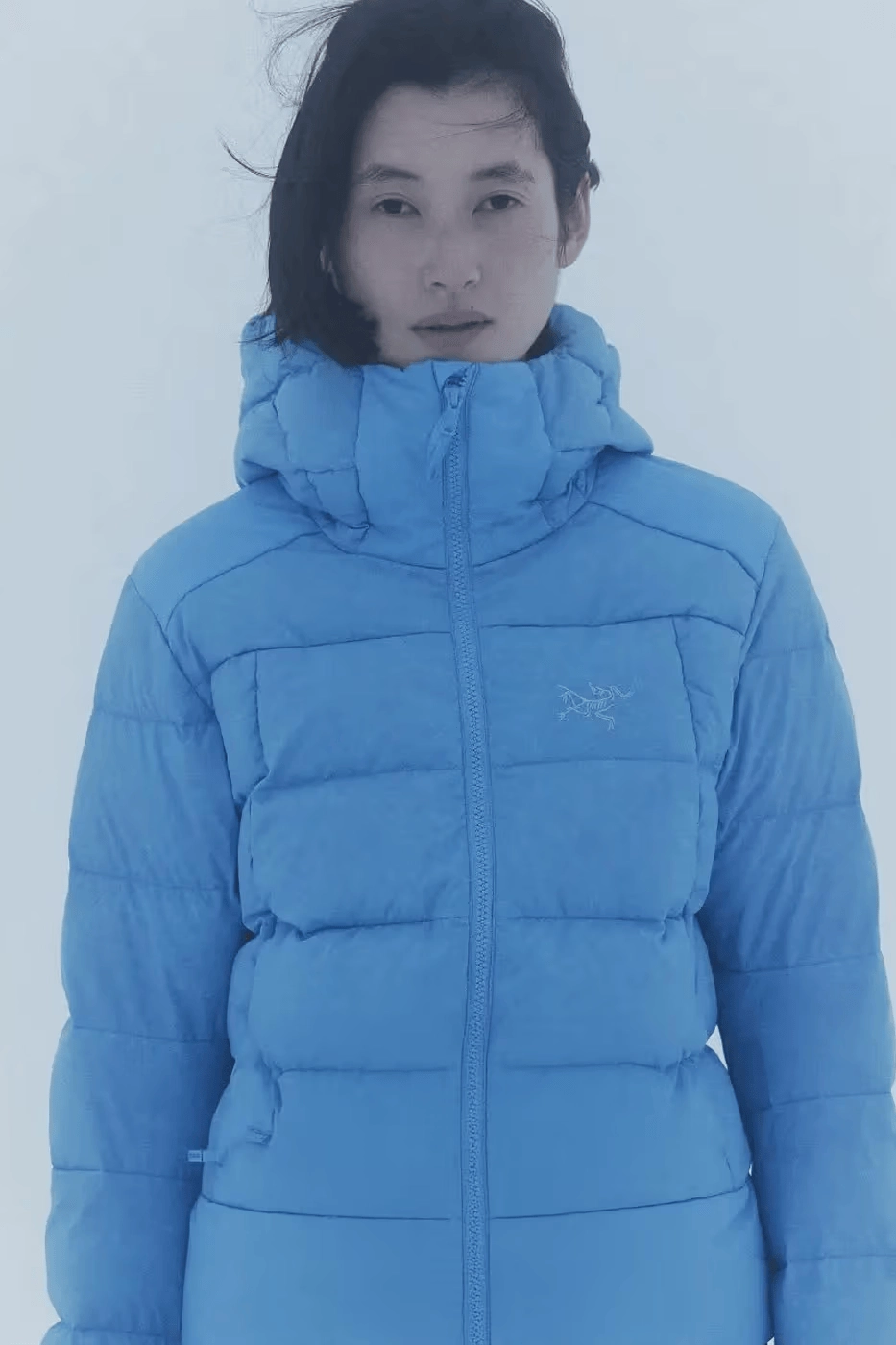femme portant une doudoune bleue Arc'teryx de face dans la neige