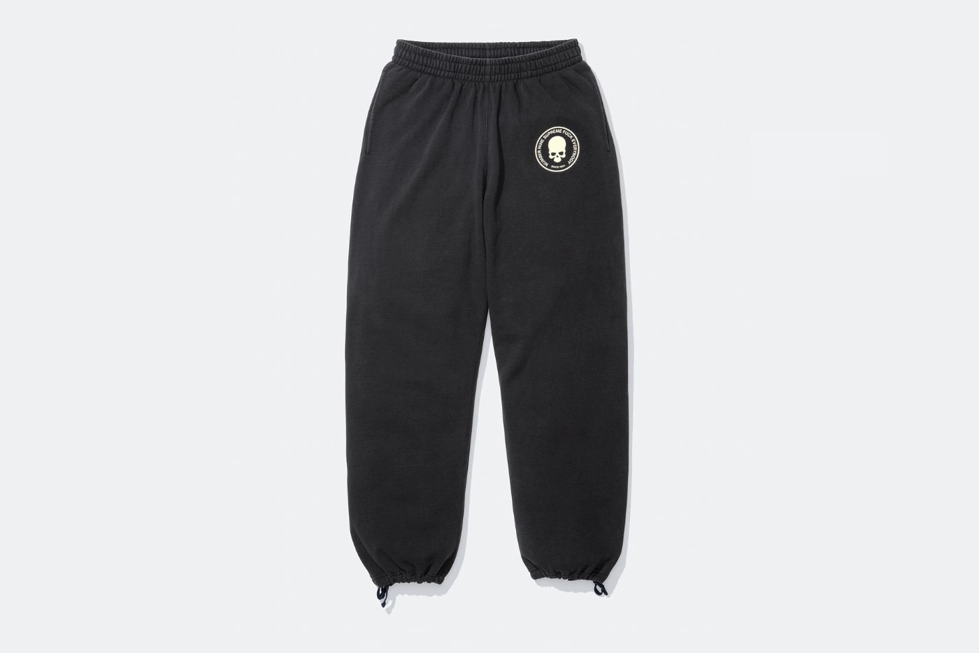 pantalon noir Supreme x Number (N)ine avec logo tête de mort à gauche, posé sur fond blanc