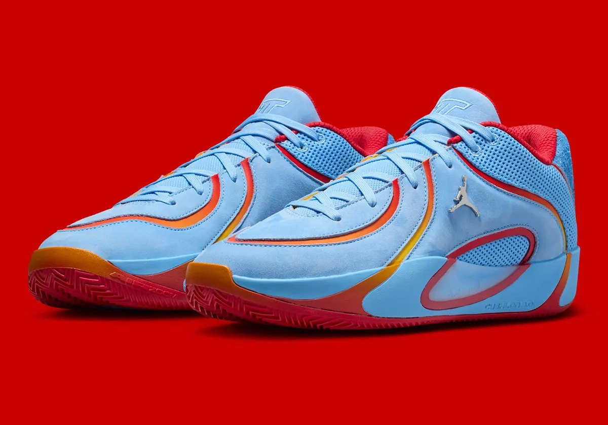 sneaker Jordan Tatum 4 bleu et rouge posée sur fond rouge avec détails orange