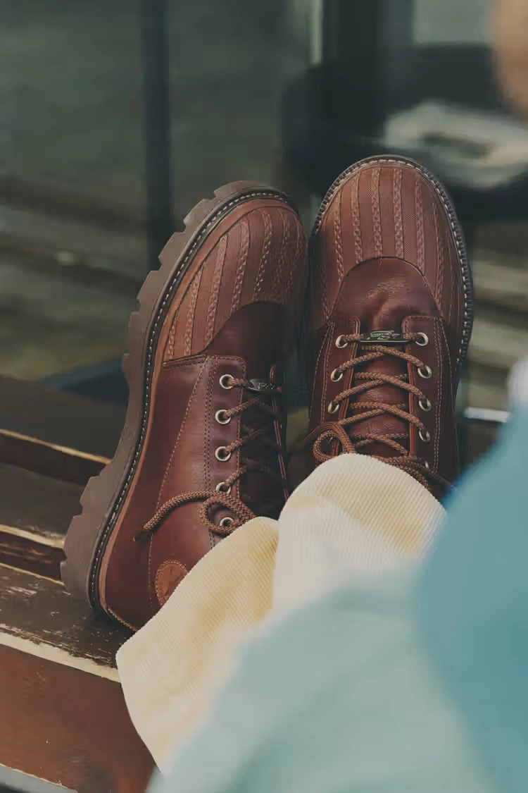 brown leather Converse 1908 Bronco boots on a wooden bench, worn with light pants