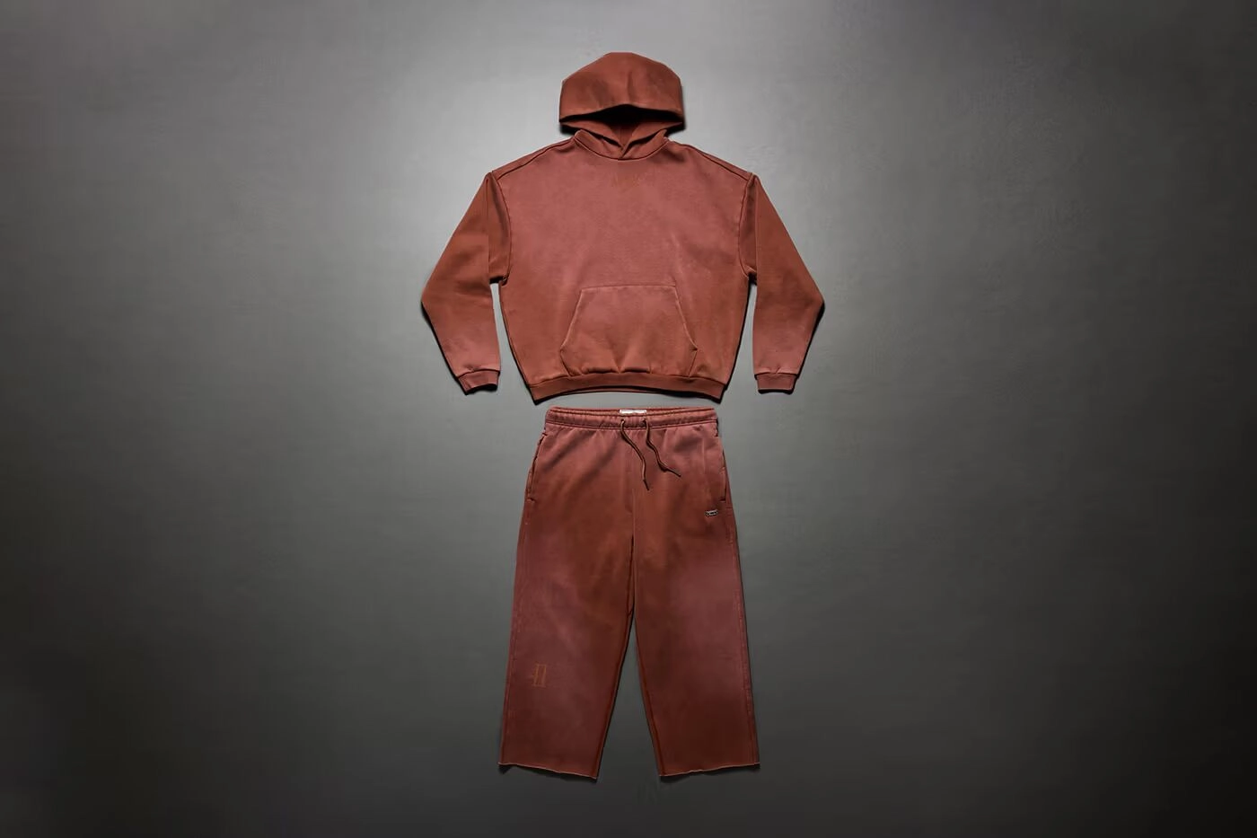 Hoodie et pantalon Nike marron rouille posés sur fond gris sombre