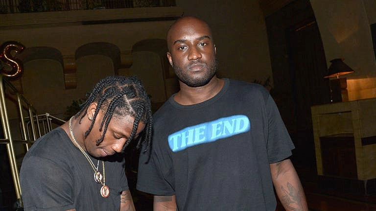 Travis Scott et Virgil Abloh portant des t-shirts noirs avec inscriptions dans un intérieur sombre