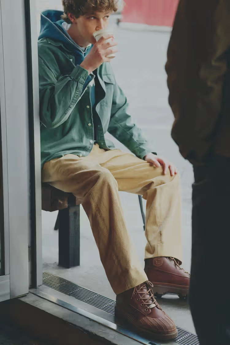 person wearing brown Converse 1908 Bronco boots, sitting, drinking coffee