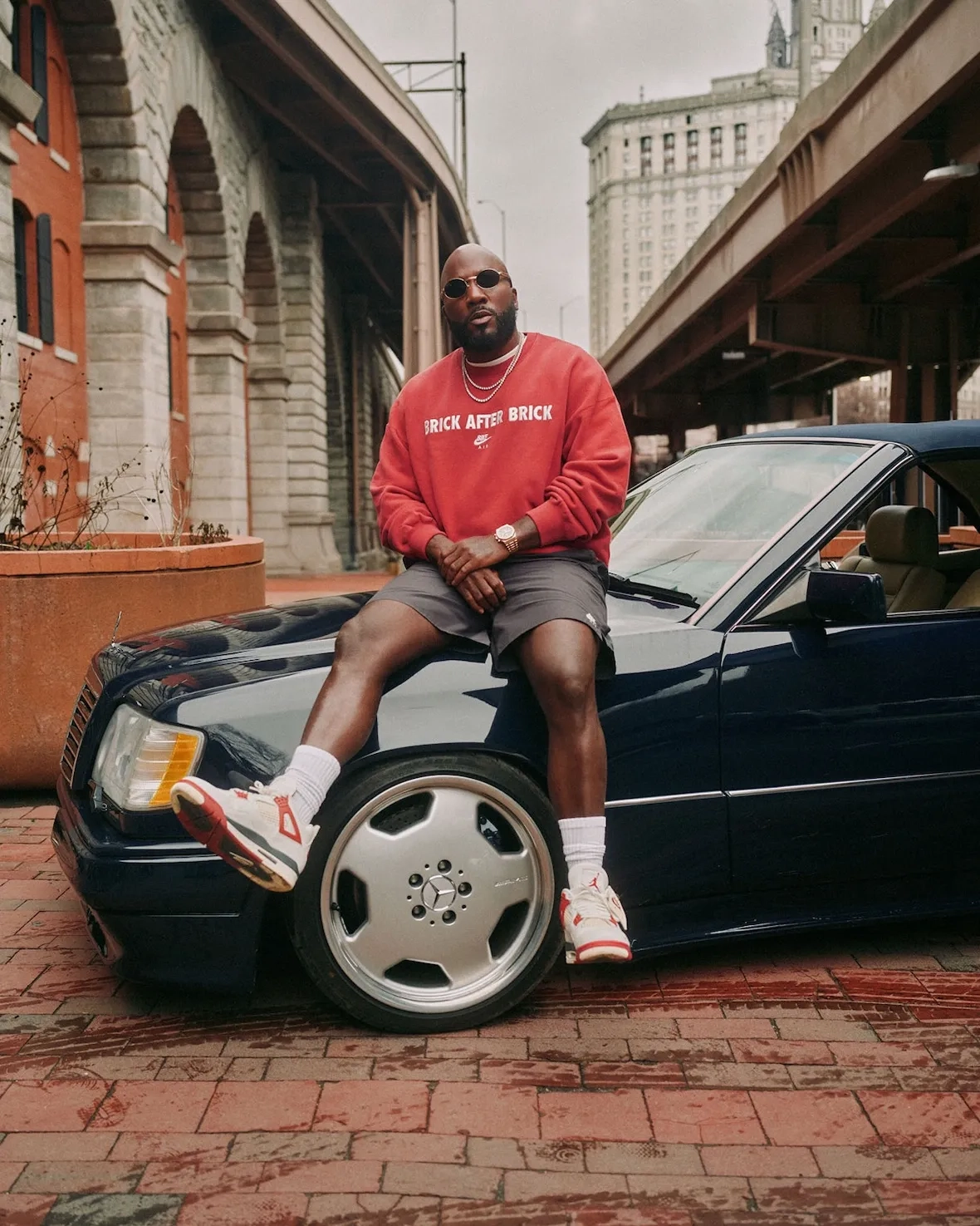 Jeezy sitting on a Mercedes with the Air Jordan 4 Sail Cinnabar on his feet