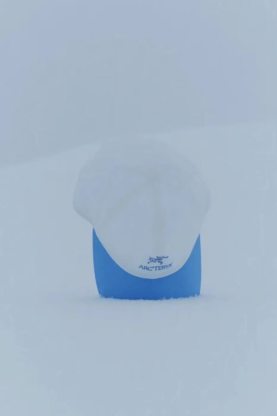 casquette Arc'teryx avec logo, posée dans la neige, fond blanc