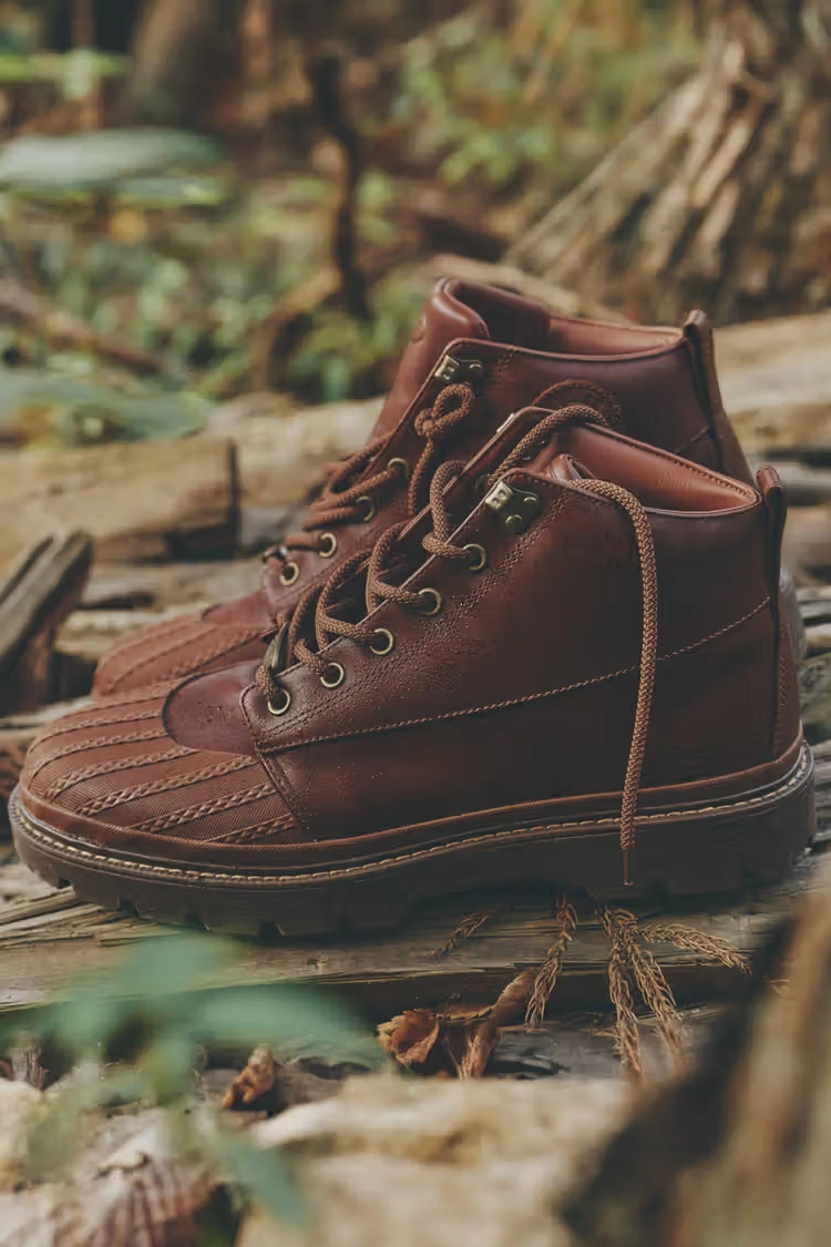 deux bottes Converse 1908 Bronco marron sur fond de nature avec feuilles et troncs