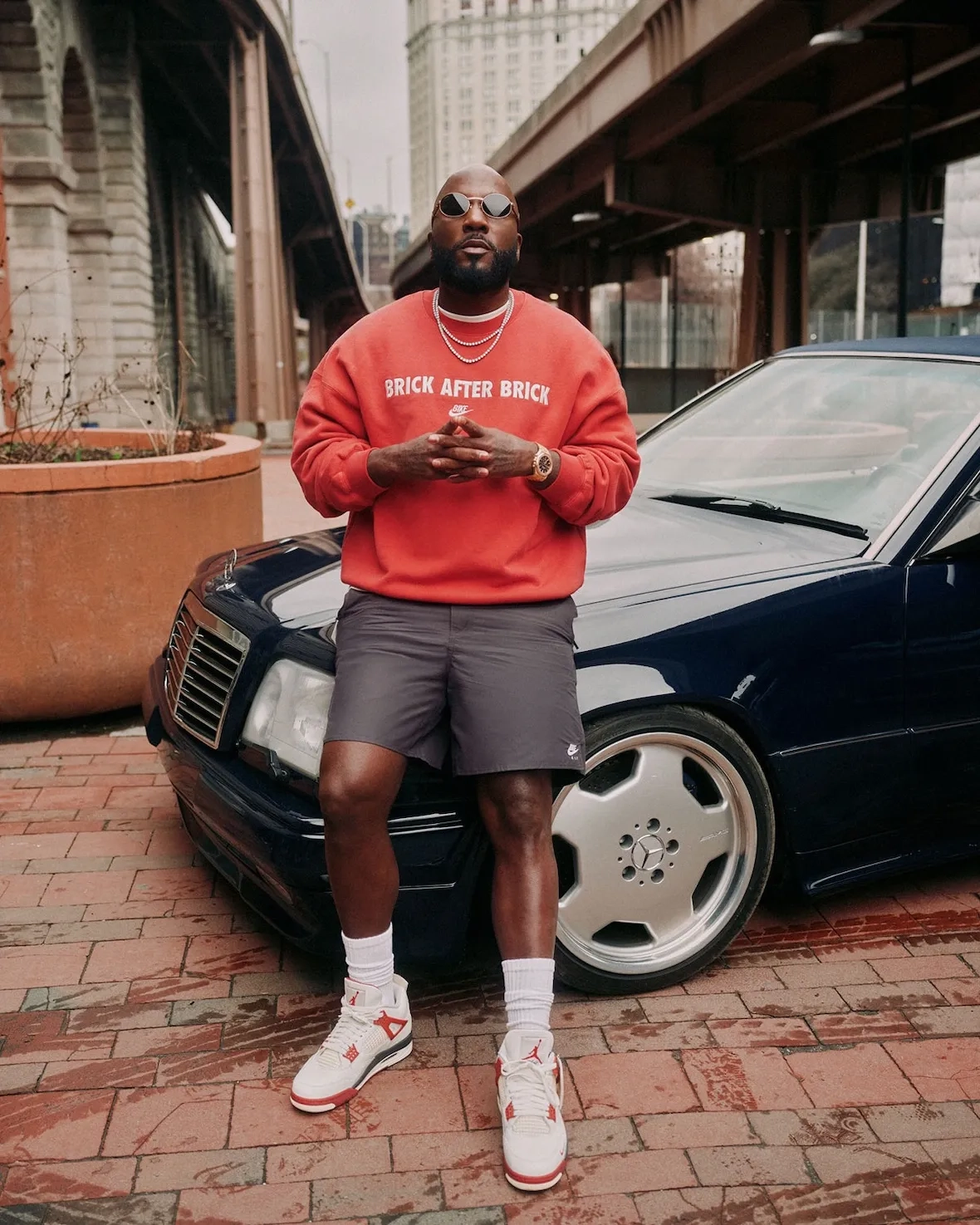 Jeezy sitting on a Mercedes wearing the Air Jordan 4 Sail Cinnabar