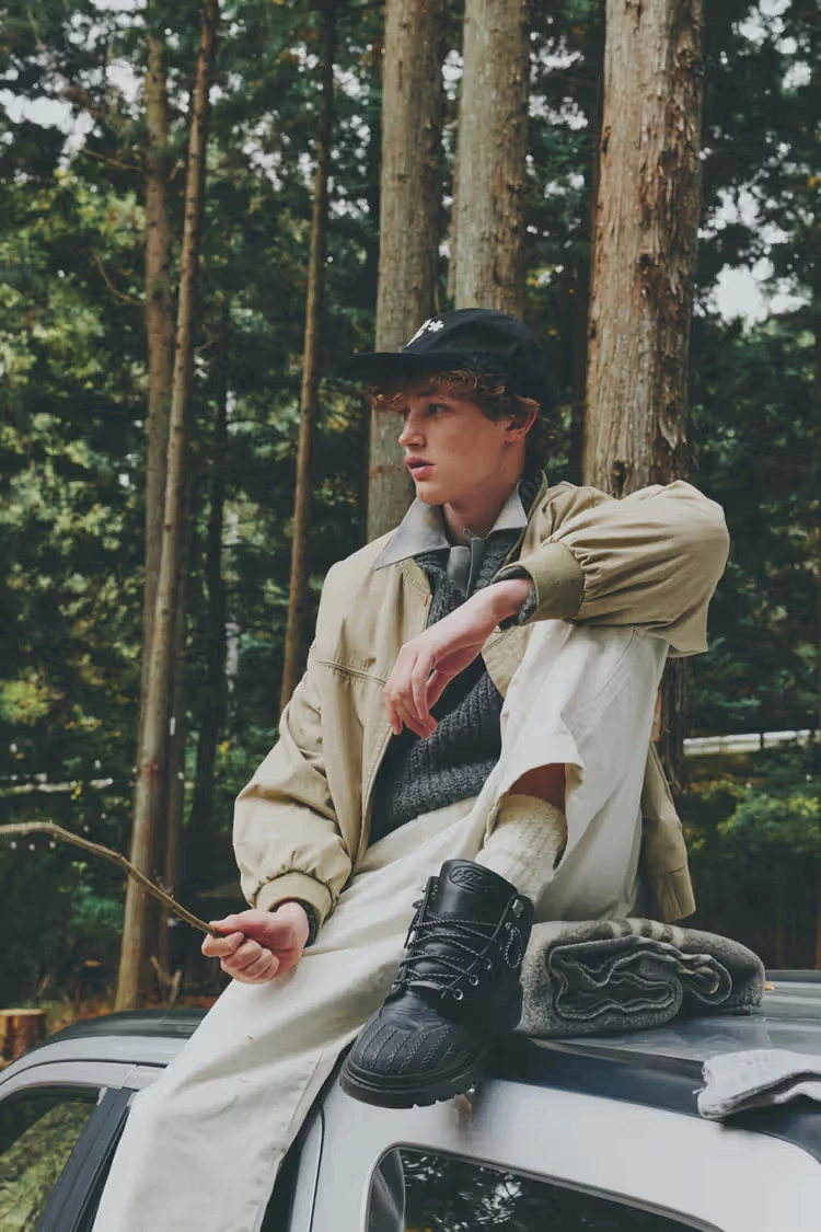 young man wearing black Converse 1908 Bronco boot in the forest, sitting on a car
