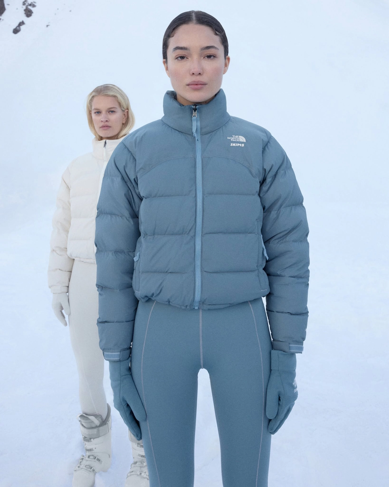 Femme en doudoune The North Face x Skims bleue et gants assortis dans la neige