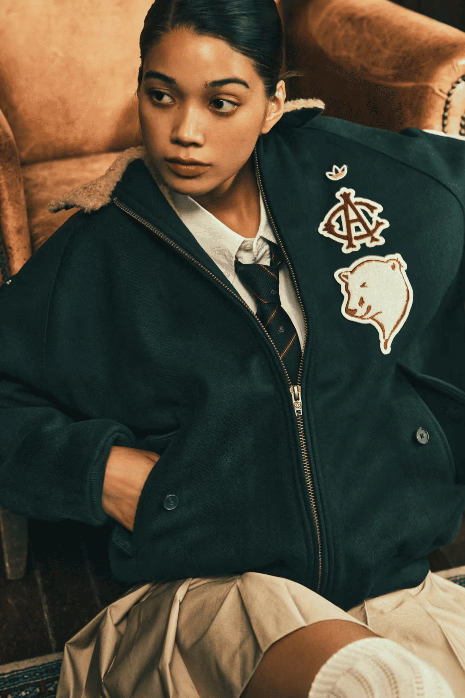 woman wearing a black CLOT jacket with bear patch on a couch