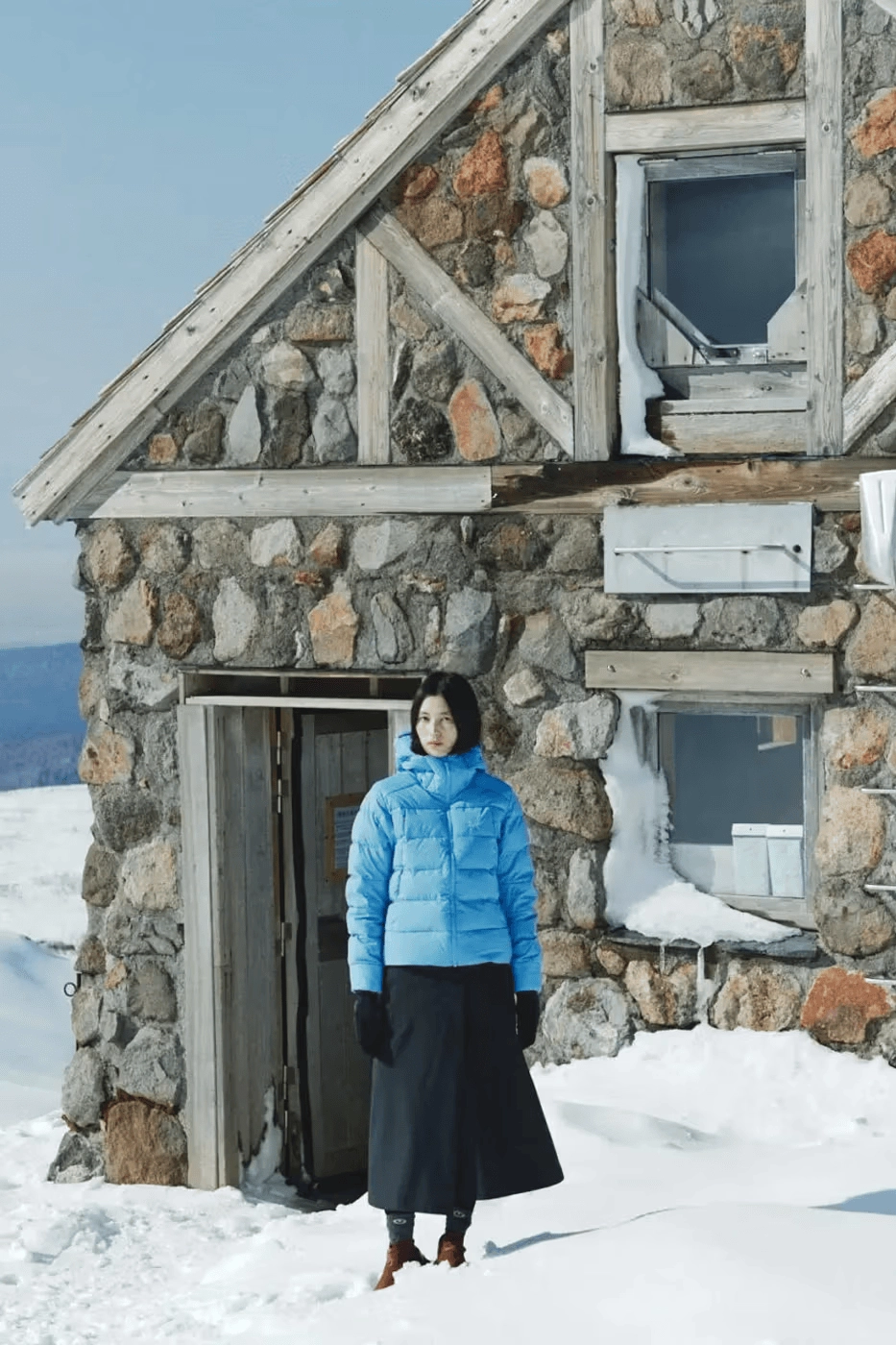 vu d'ensemble de la doudoune Arc'teryx Glacial bleue devant un chalet