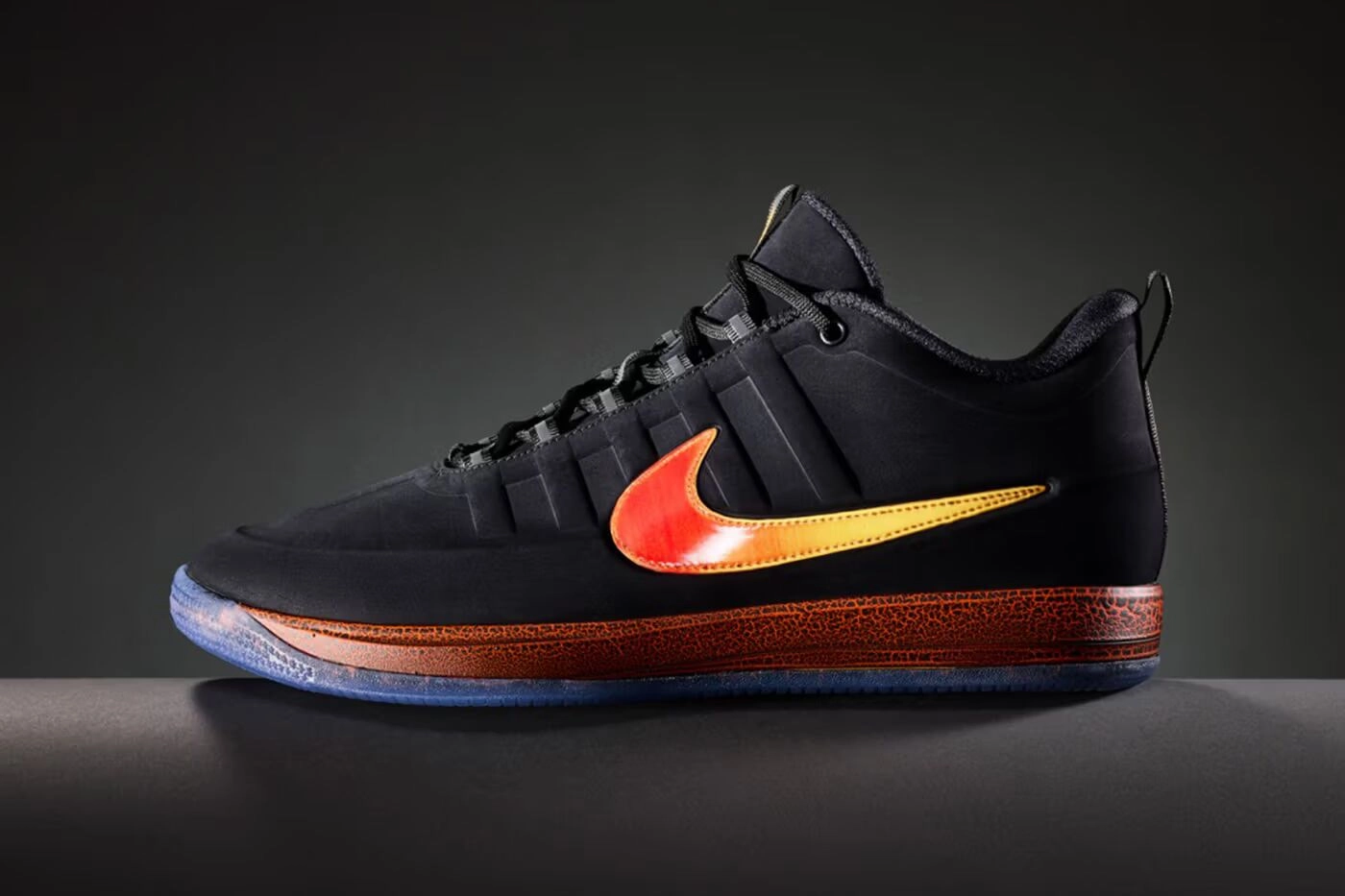Profil latéral gauche de sneaker Nike noire avec swoosh orange et semelle texturée sur fond noir