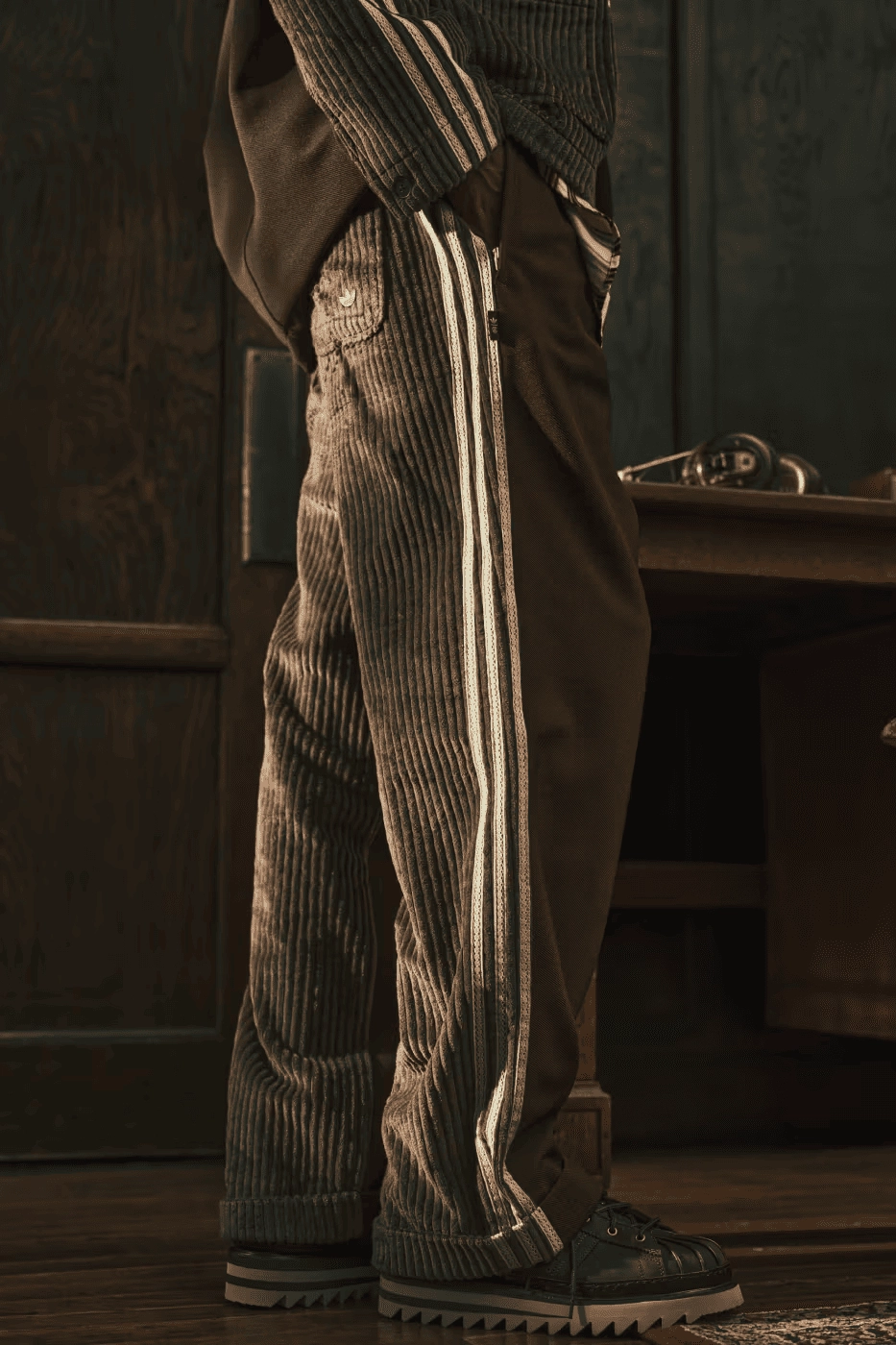 brown corduroy Adidas pants with white stripes, worn standing
