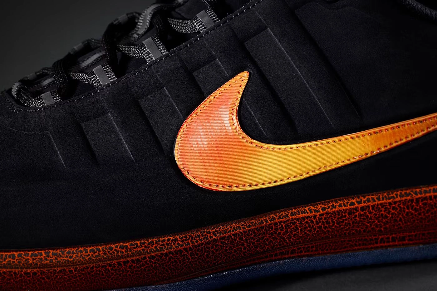 Détail latéral d'une sneaker Nike noire avec swoosh orange dégradé et semelle texturée