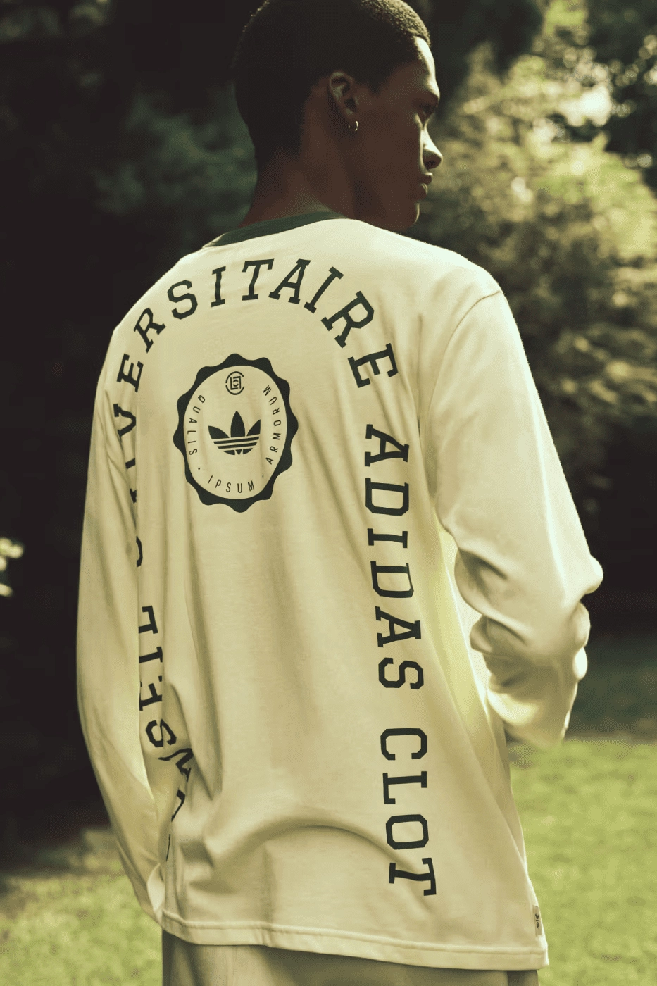 homme portant un t-shirt blanc CLOT x Adidas avec logo arrière, en extérieur