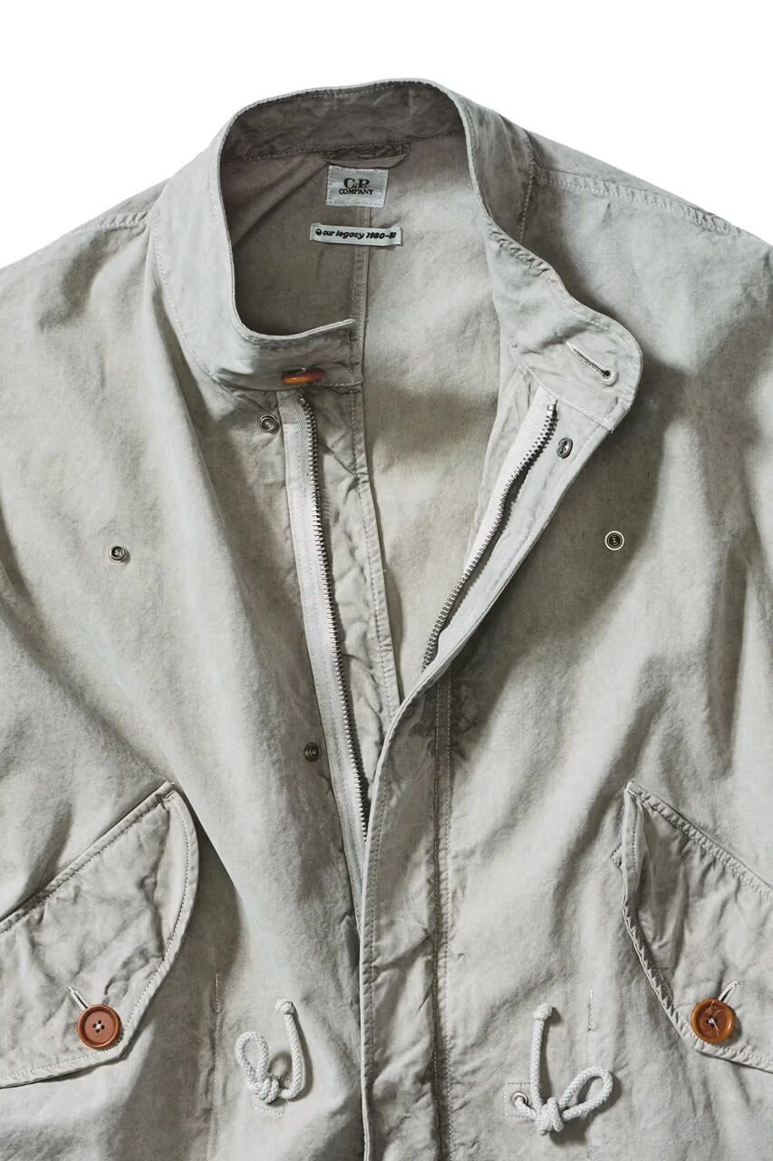 Veste grise avec zip ouverte, collaboration CP Company et Our Legacy, sur fond blanc