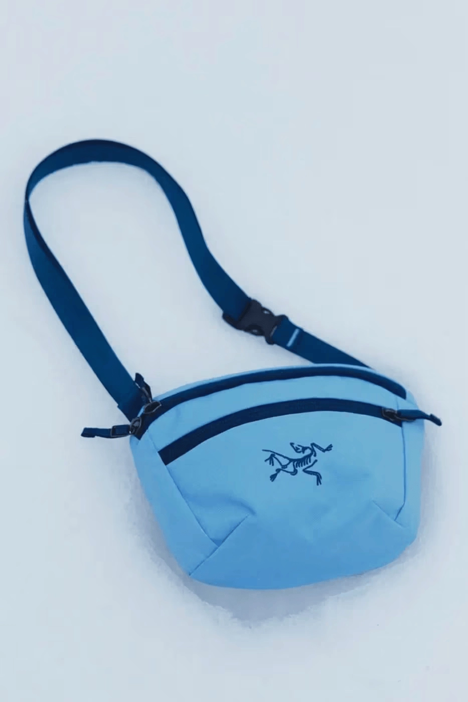 sacoche Arc'teryx bleue avec logo posée sur neige blanche